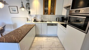Eine moderne Küche mit weißen Schränken, einer Granit Arbeitsplatte, einem Geschirrspüler und einem eingebauten Backofen.