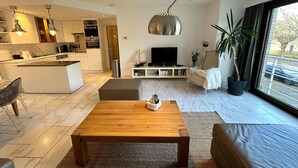 Ein moderner Wohnraum mit Küche, Essbereich und einer Sitzecke mit Fernseher.