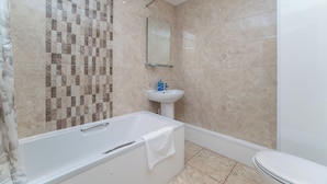 A bathroom with a bathtub, sink, and toilet.