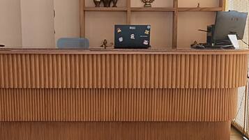 A reception desk with a ceiling fan, an air conditioning unit, and a shelf with decorative items.