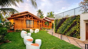 Una casa in legno con un balcone, un prato erboso e mobili da giardino.