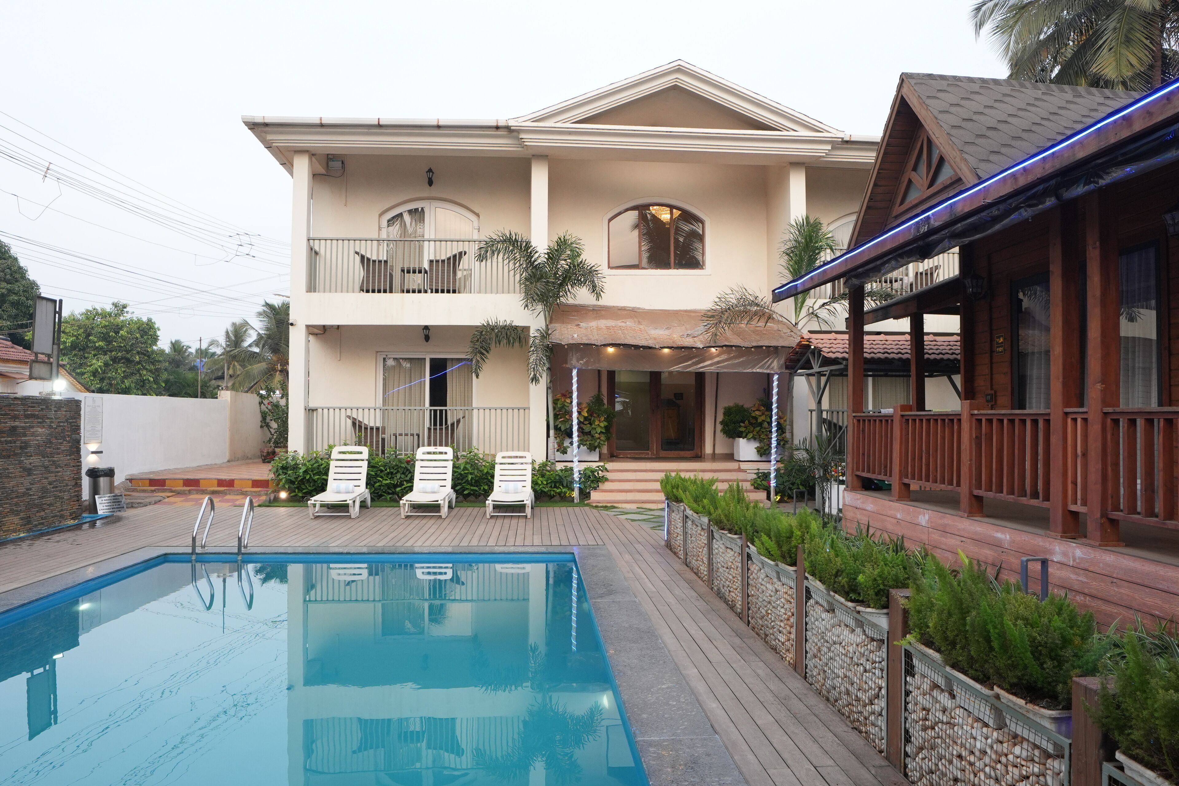 A two-story house with a swimming pool, a covered patio, and a wooden deck.