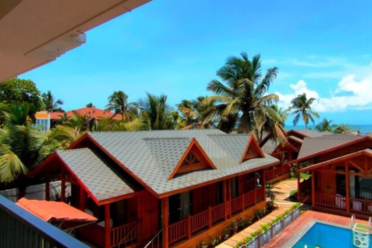 Un resort con varias cabañas de madera, una piscina y palmeras.