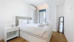 Een moderne slaapkamer met een bed, nachtkastje en spiegel.