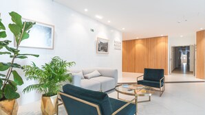 Een moderne lobby met een bank, twee fauteuils, een bijzettafeltje en potplanten.