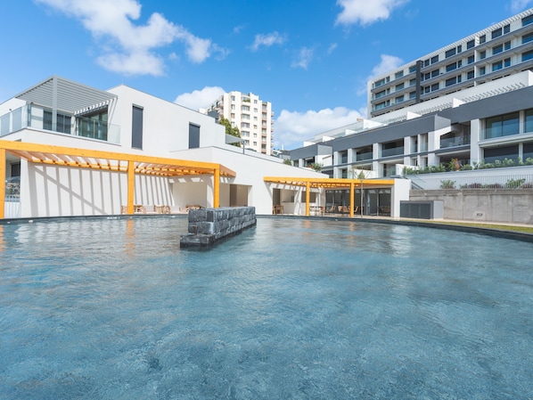 A modern building with a pool area, outdoor seating, and a view of other buildings.