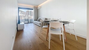 Een moderne eetruimte met een ronde tafel, witte stoelen en uitzicht op een balkon met stadszicht.