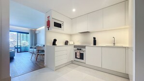 Een moderne keuken met witte kasten, een ingebouwde magnetron en een gasfornuis.