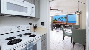 Une cuisine avec un four blanc, un four à micro-ondes et un coin repas comprenant des chaises et une table.