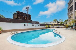 A swimming pool with a white wall and a metal fence. - Kona Plaza#302: Third Floor, Ocean View in Heart of Kona Town, Ac & Elevators (Kailua Kona)