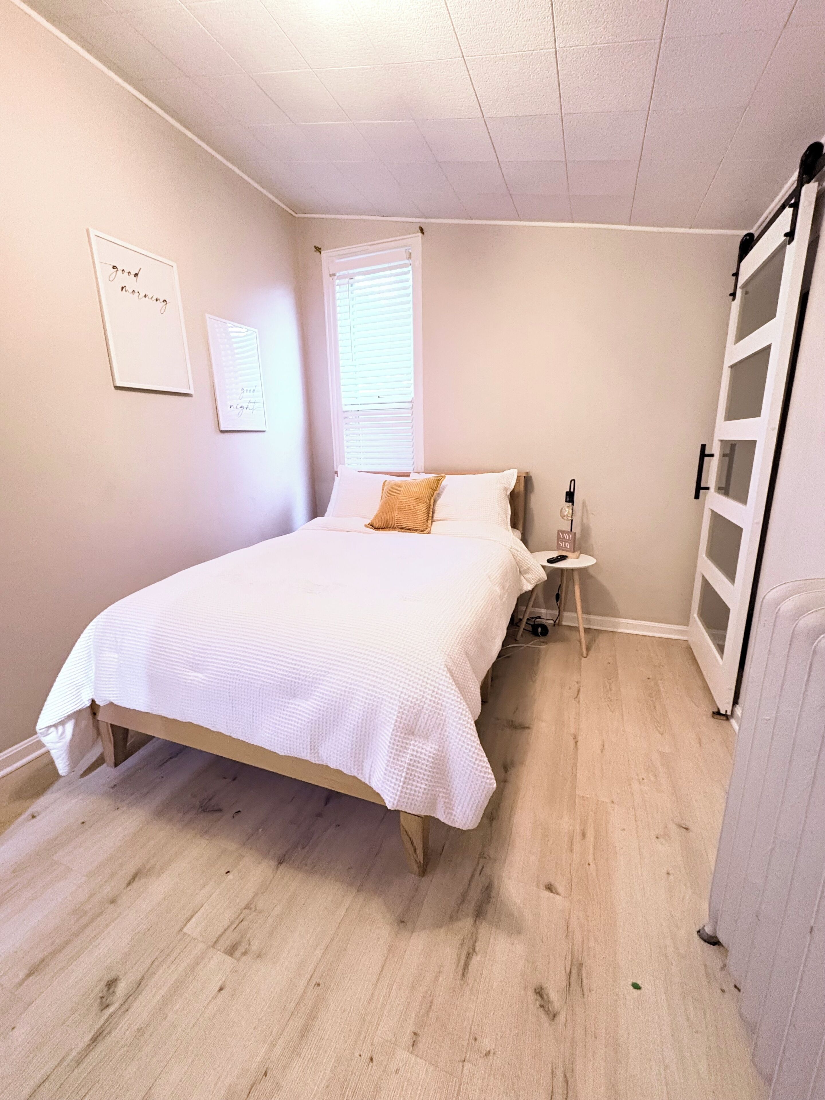 Ein Schlafzimmer mit einem Bett, einem Nachttisch, einem Fenster mit Jalousien und einem Kleiderschrank.