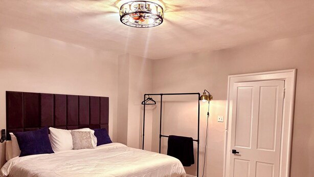 Een slaapkamer met een bed, een kledingkast, een kledingroede en een deur.