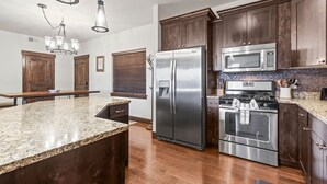 A modern kitchen with dark wood cabinets, stainless steel appliances, granite countertops, and a central island. - Moose Mgmt at Bear Hollow Ridge 2207: Hot Tub, Pool, Hiking Trails, Shops-Dining (Park City)