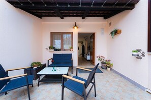 Relax in this serene outdoor seating area with a table and four chairs, surrounded by lush greenery and a natural ambiance.