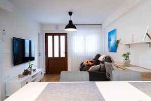 Relax in this stylish living room with a flat-screen TV, comfortable sofa, and dining area.