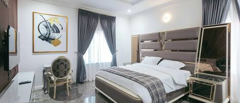 A modern hotel room with a large bed, a bedside table, a chair, a TV, and a painting on the wall.