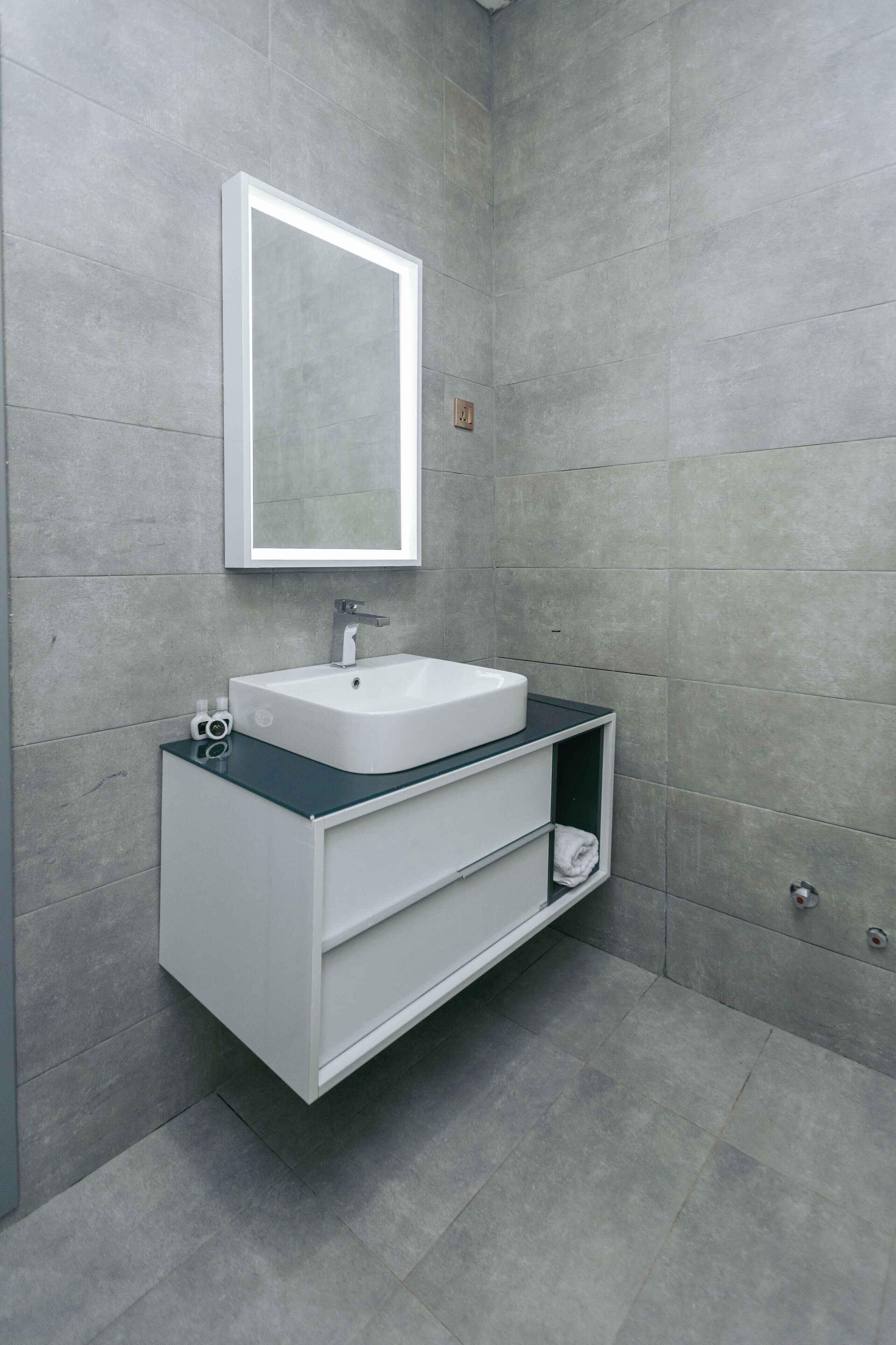 A modern bathroom with a white sink, a mirror, and a built-in shelf.