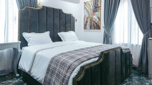 A modern hotel room with a large bed, marble flooring, and a decorative ceiling. - Phoenix Luxury Apartments  (Abuja)