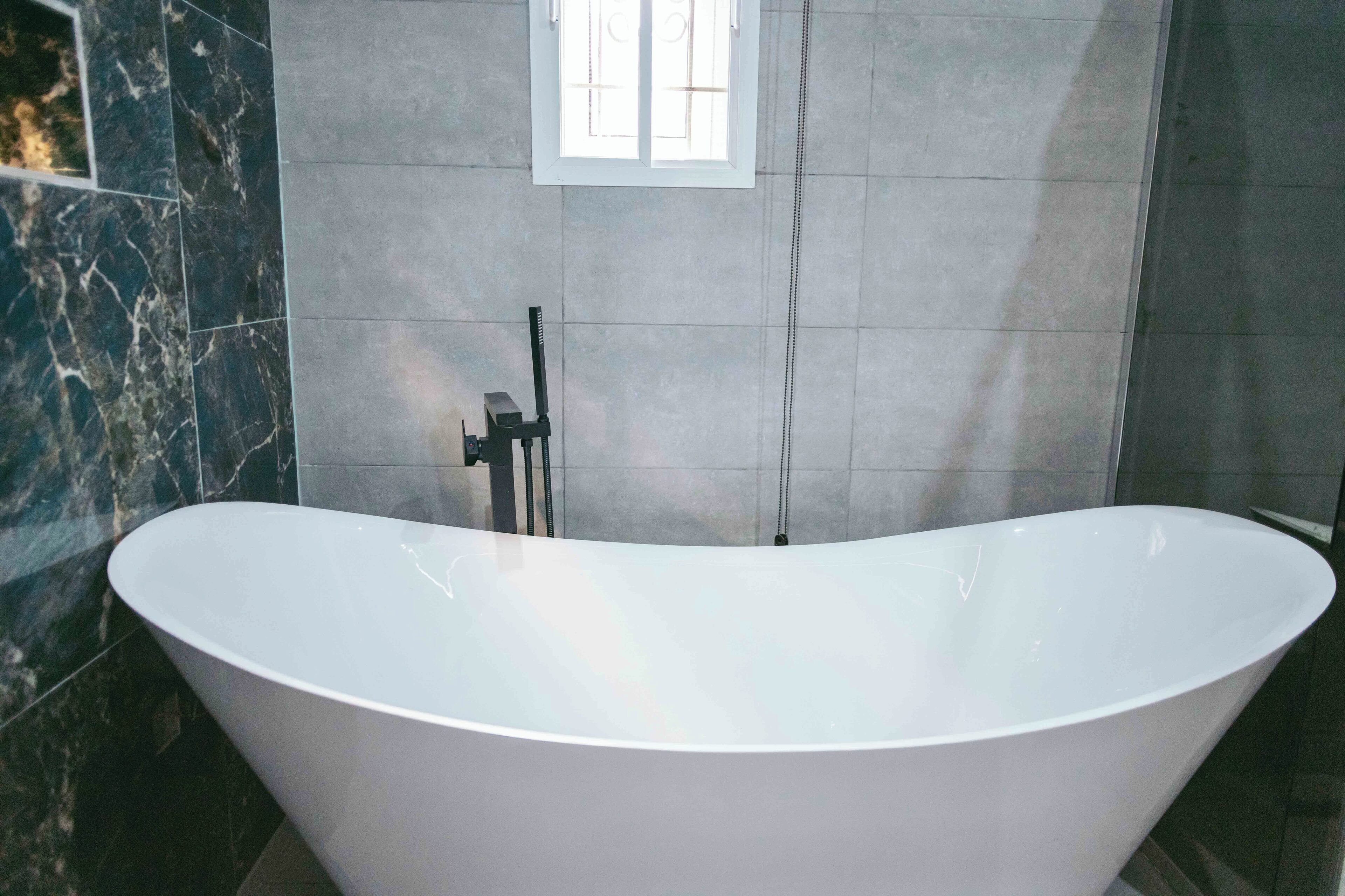 A modern bathroom with a freestanding bathtub, a window, and a towel rack.