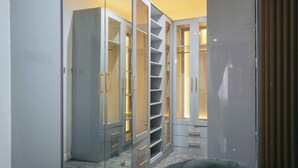 A walk-in closet with multiple shelves and drawers, featuring a modern design with metallic handles and illuminated shelves. - Phoenix Luxury Apartments  (Abuja)