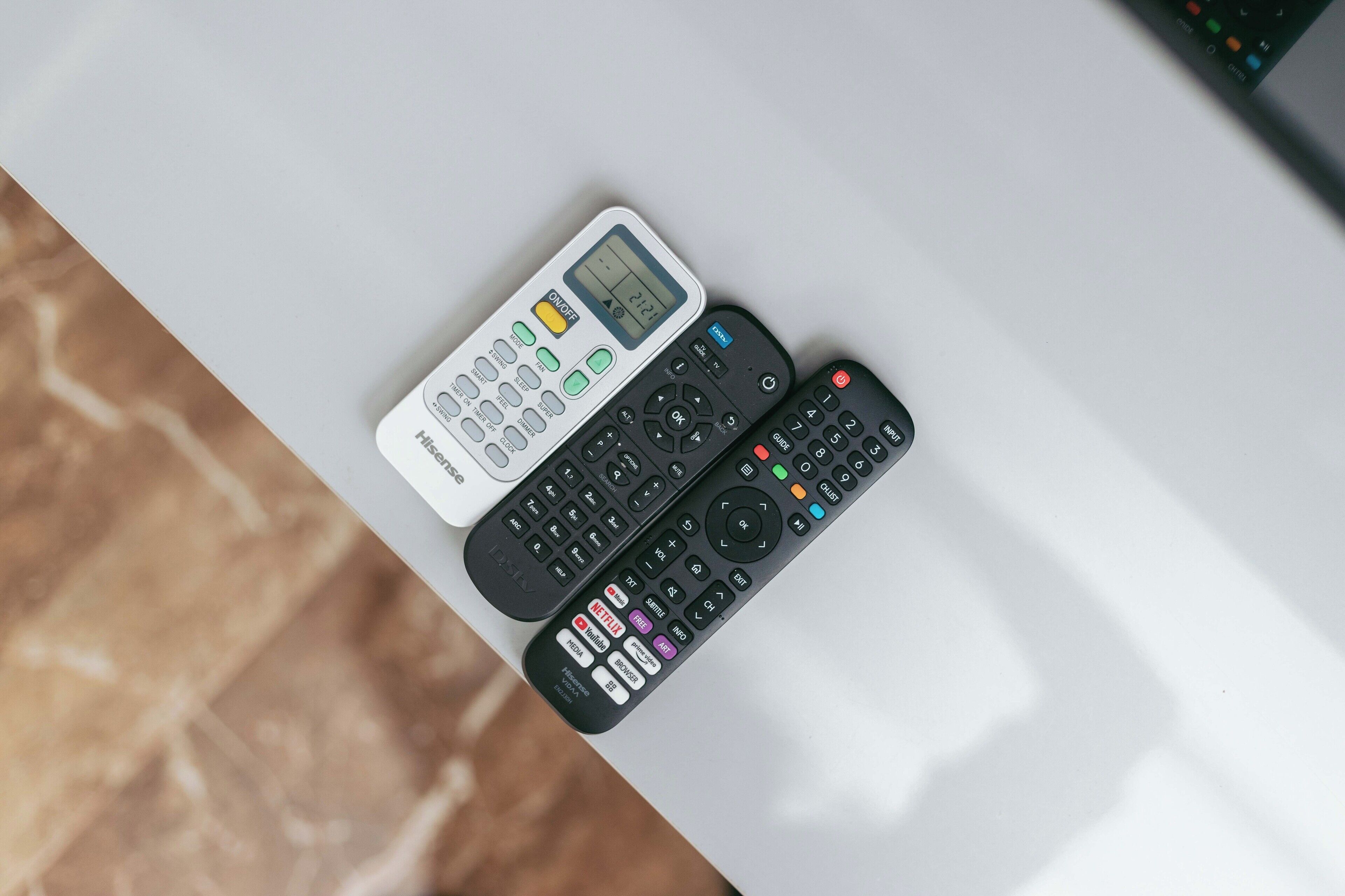 Three remote controls on a white surface.