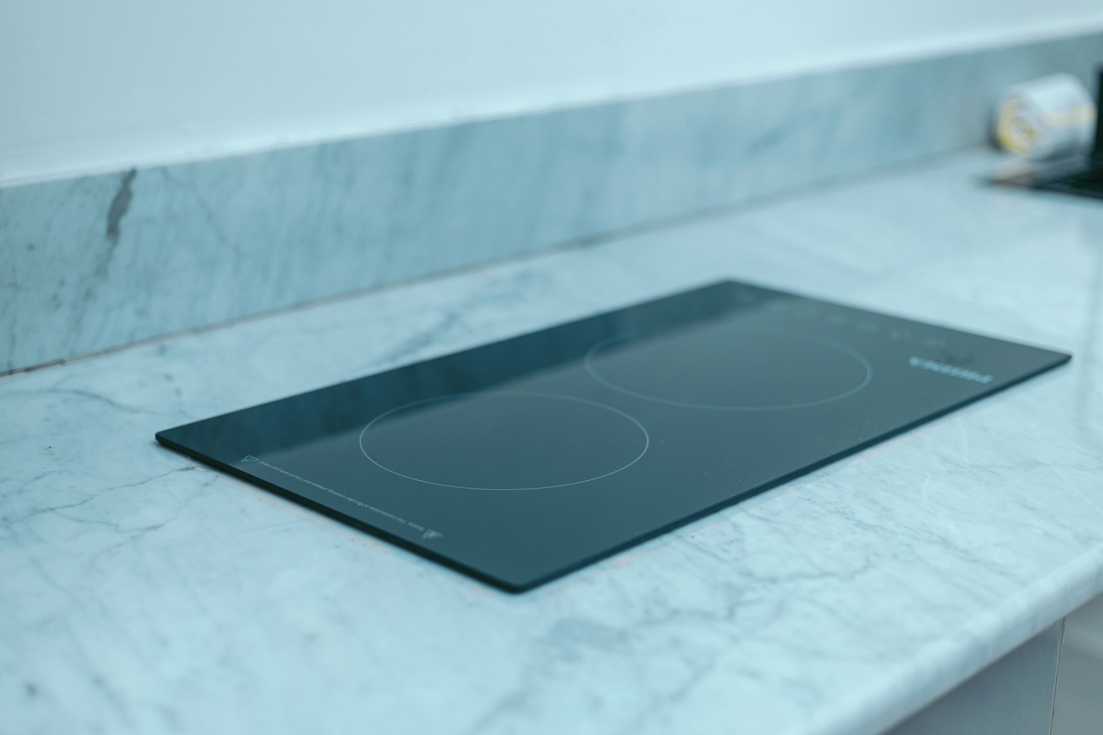 A black induction cooktop on a marble countertop.