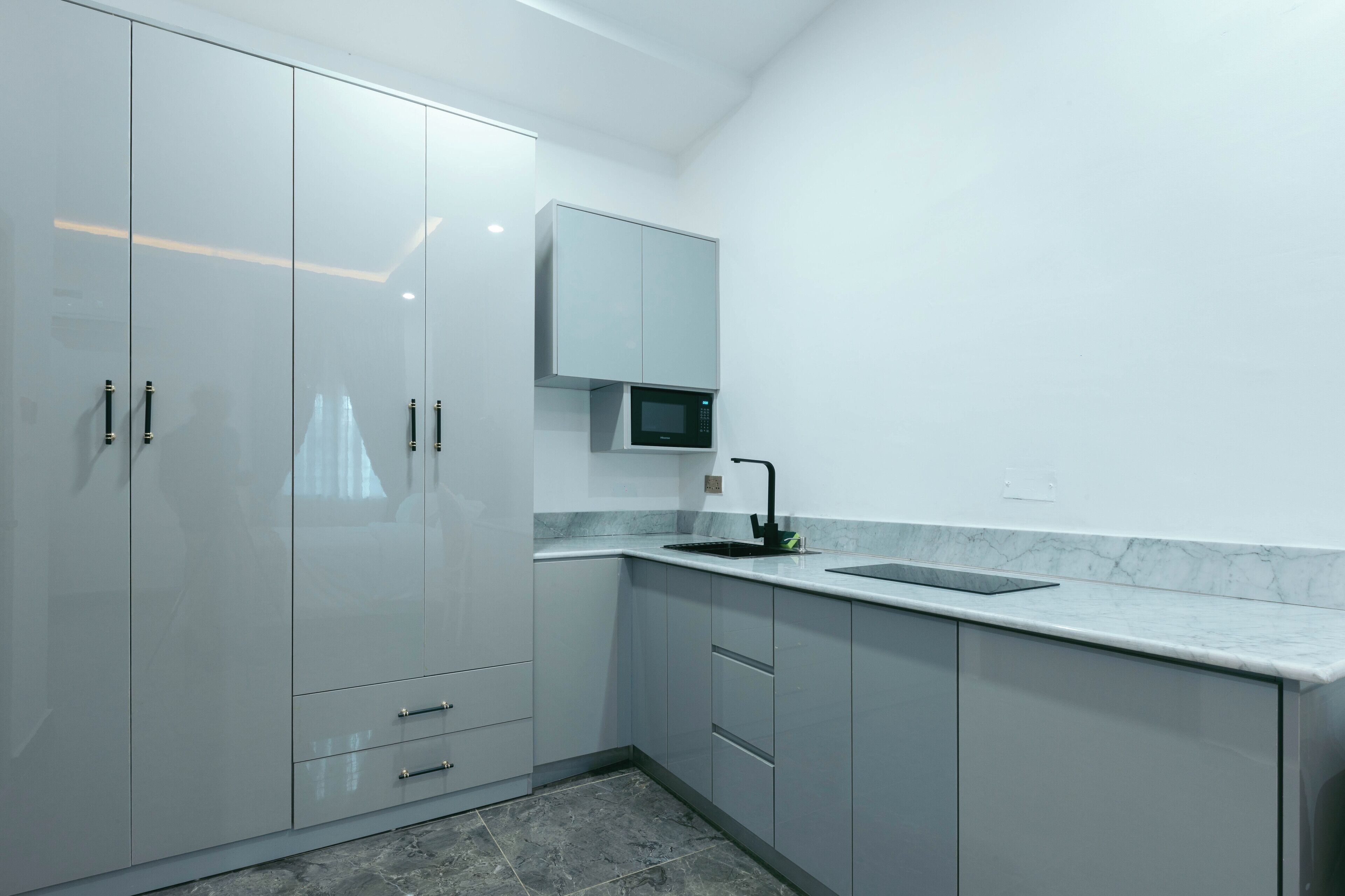 A modern kitchen with a built-in microwave, a sink, and grey cabinets.
