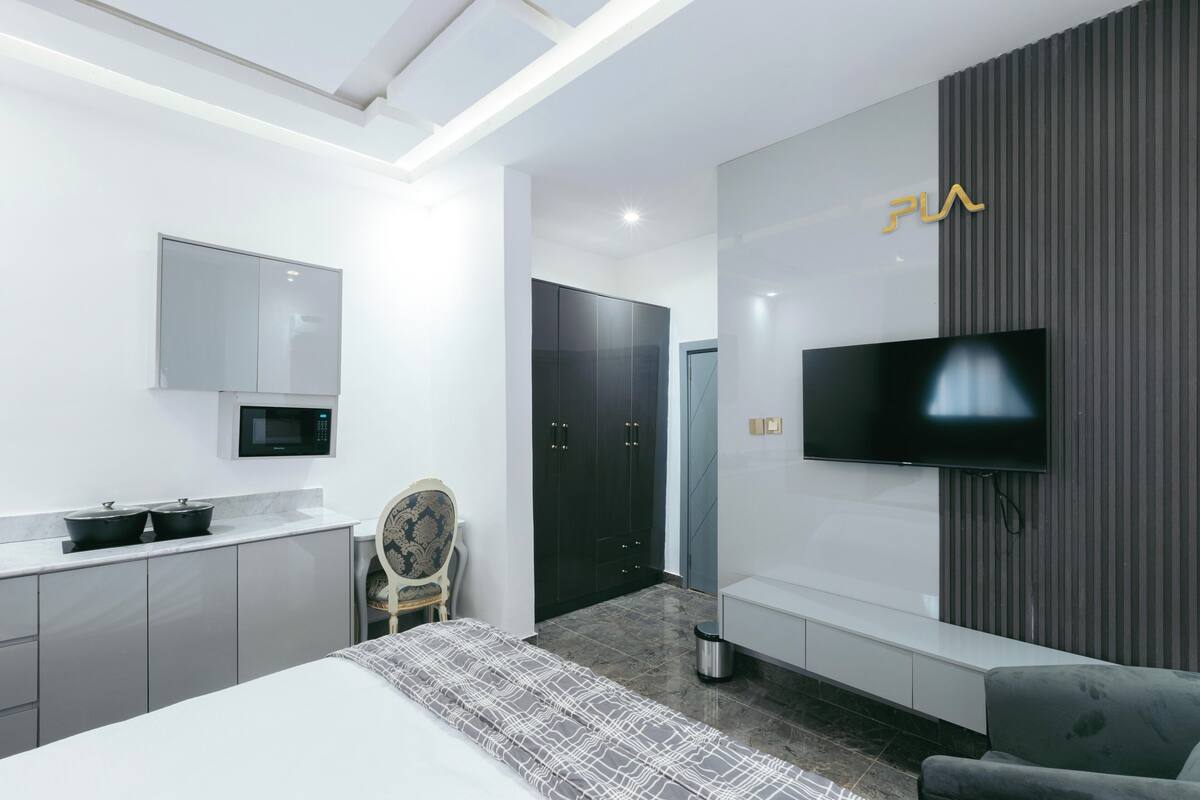 A modern hotel room with a bed, a TV, a desk, and a chair.