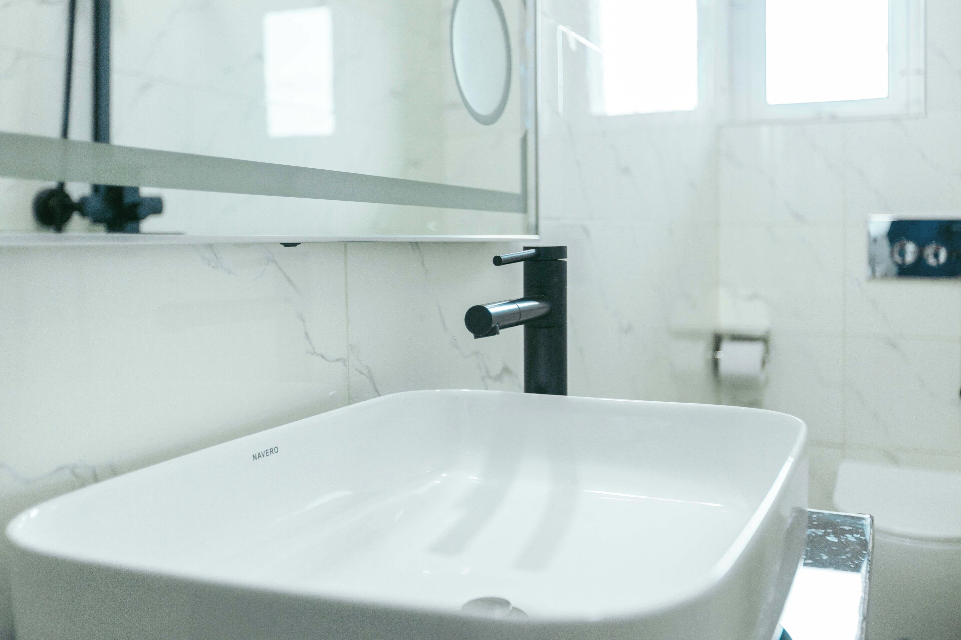 A bathroom with a white sink, a mirror, and a toilet.