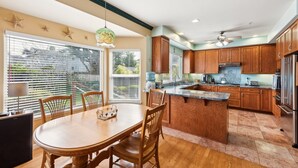 Una cocina moderna con armarios de madera, una isla central y una zona de comedor con mesa y sillas.