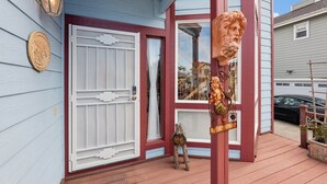 Una casa con puerta roja, puerta de garaje blanca y un porche con una escultura.