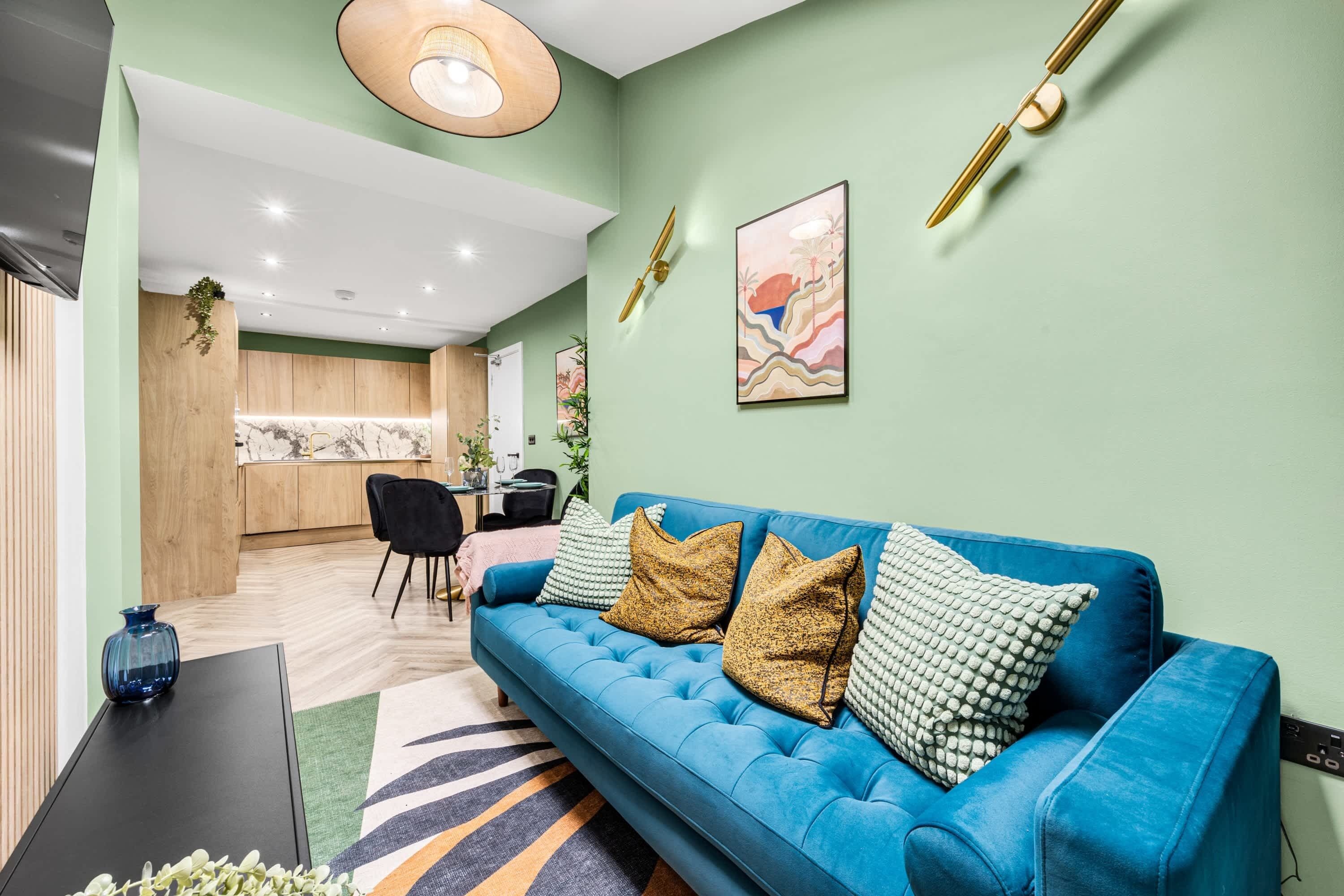 Una sala de estar moderna con un sofá azul, una mesa de centro negra y un tapete estampado.