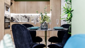 A modern dining area with a marble backsplash, a wooden kitchen in the background, and a vase with flowers on the table.