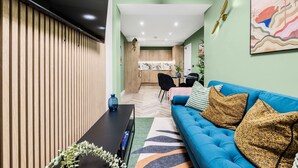 A modern living room with a blue sofa, a black coffee table, and a wooden slatted wall.