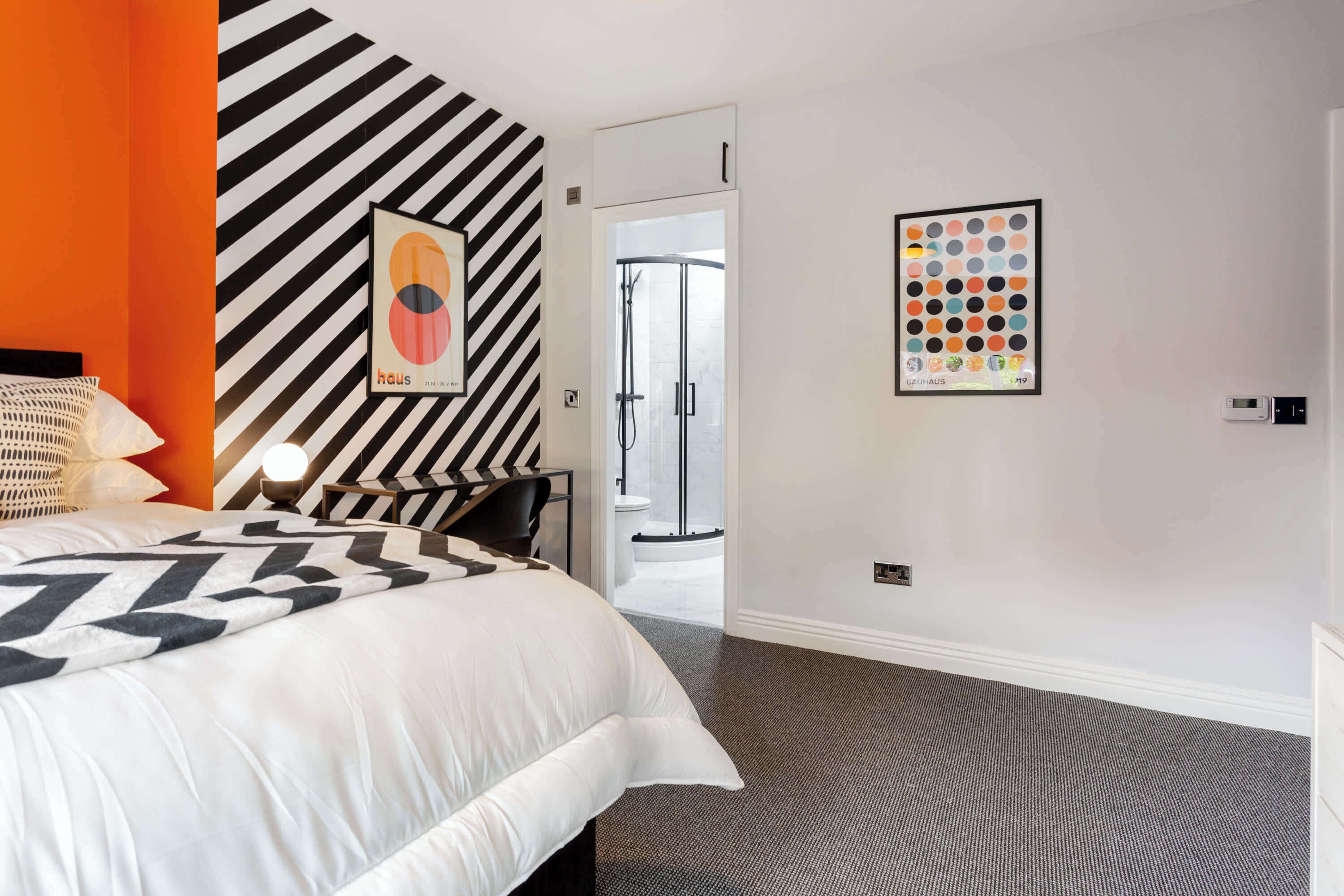 Een hotelkamer met een bed, nachtkastje, stoel en deur naar een badkamer.