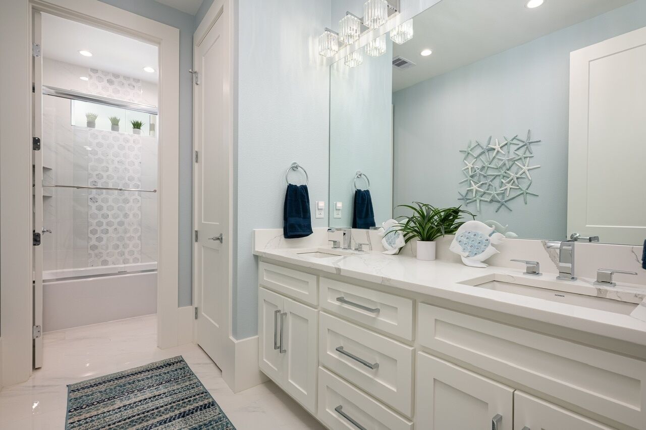 A modern bathroom with a large mirror, two sinks, and a shower area.