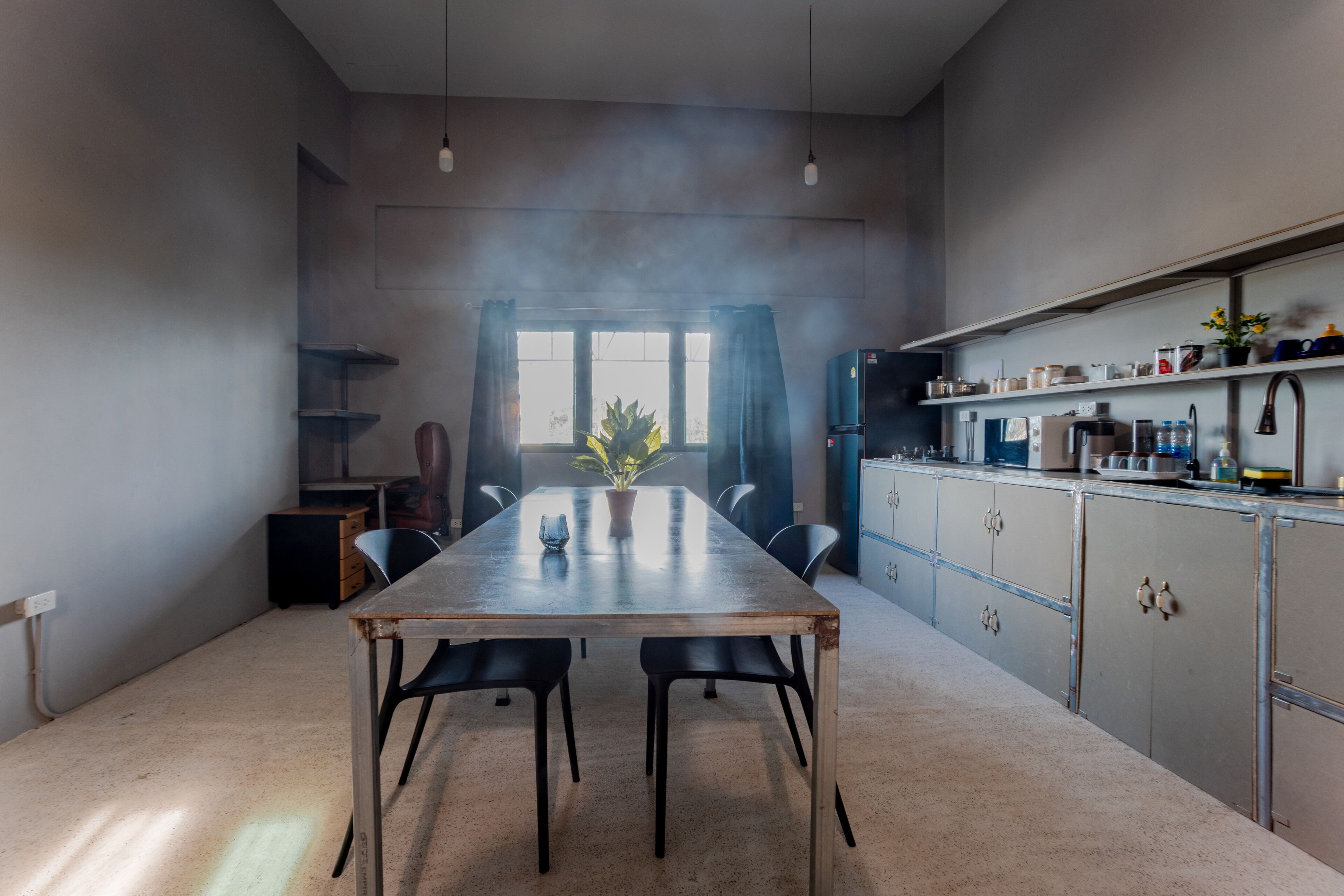 Una cocina moderna con una amplia mesa de comedor, sillas negras y una planta en maceta.