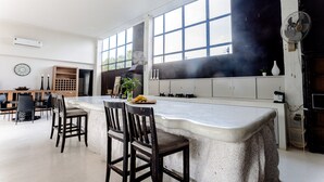 Une cuisine dotée d’un grand îlot central, de tabourets de bar et d’un coin repas avec des chaises et une table.