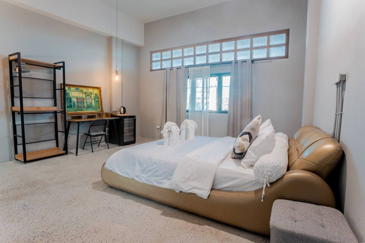 A modern bedroom with a large bed, a desk, and a chair.