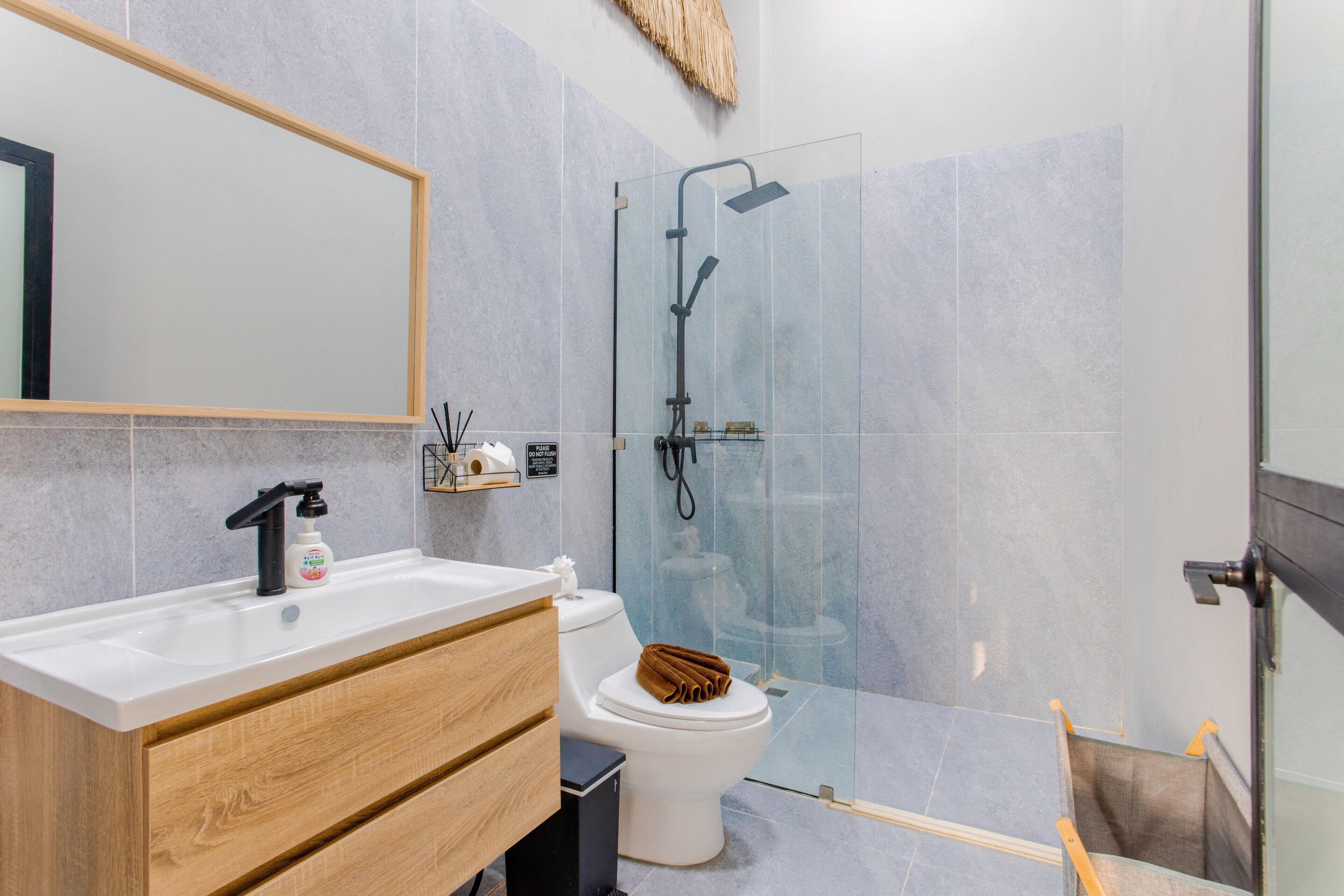 Un baño moderno con cabina de ducha de vidrio, un lavamanos blanco y un mueble de tocador de madera.