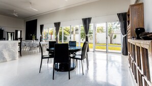 Un vaste espace dédié à la salle à manger, avec une table ronde et des chaises, de grandes fenêtres dotées de rideaux et une vue sur l’extérieur.