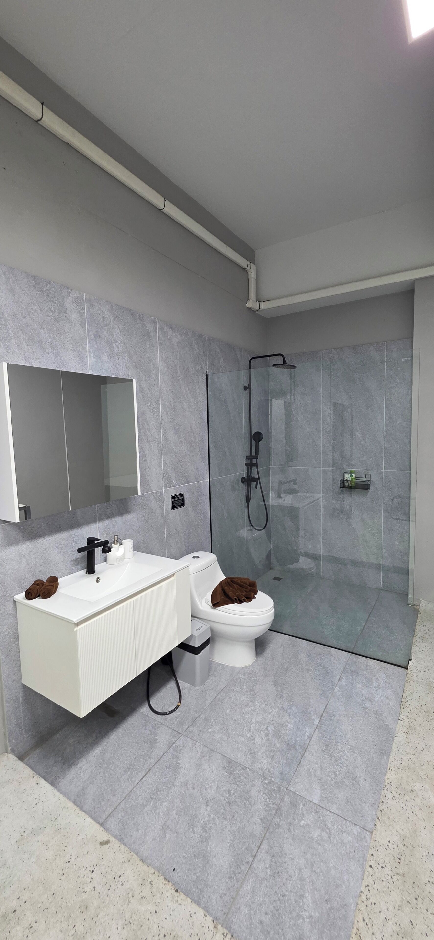 A modern bathroom with a white vanity, a toilet, and a glass-enclosed shower.