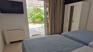 Hotellihuone, jossa on kaksi sänkyä, televisio, vaatekaappi ja näkymä ulos.