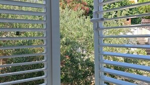 A view through white blinds of a garden with various plants and a small tree. - Seaview Retreat for 6 people (Tkon)