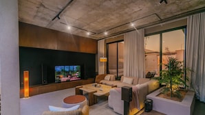 A modern living room with a flat-screen TV, comfortable seating, a coffee table, and a small plant. - Portal Chalets With Private Pool-Al Arid (Riyadh)