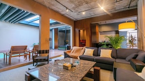 A modern living room with a sofa, coffee table, and chairs. There is a skylight, a plant, and a lamp. - Portal Chalets With Private Pool-Al Arid (Riyadh)