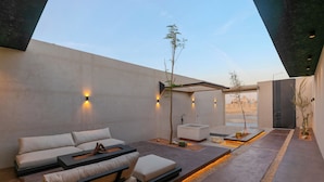 A modern outdoor living area with a sofa, a coffee table, and a small seating area. - Portal Chalets With Private Pool-Al Arid (Riyadh)