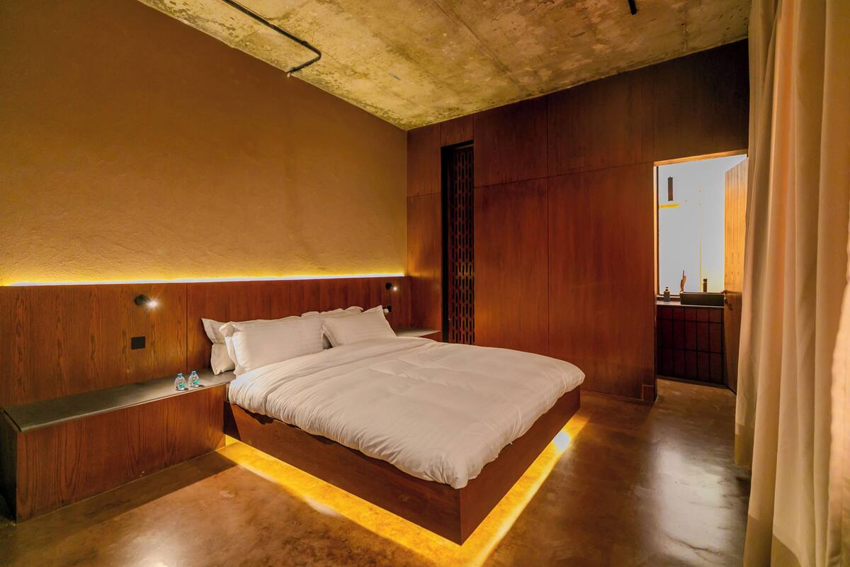 Ein modernes Schlafzimmer mit einem großen Bett, Holzvertäfelung und einer eingebauten Sitzbank.