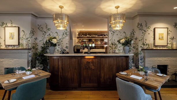 Un restaurante con barra de madera, dos candelabros y una chimenea.