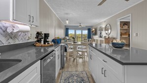 A modern kitchen with a central island, white cabinetry, and a ceiling fan.